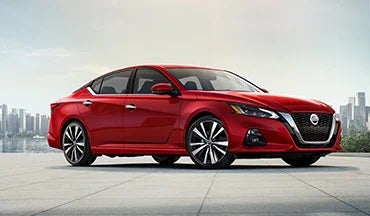 2023 Nissan Altima in red with city in background illustrating last year's 2022 model in Serra Nissan of Sylacauga in Sylacauga AL